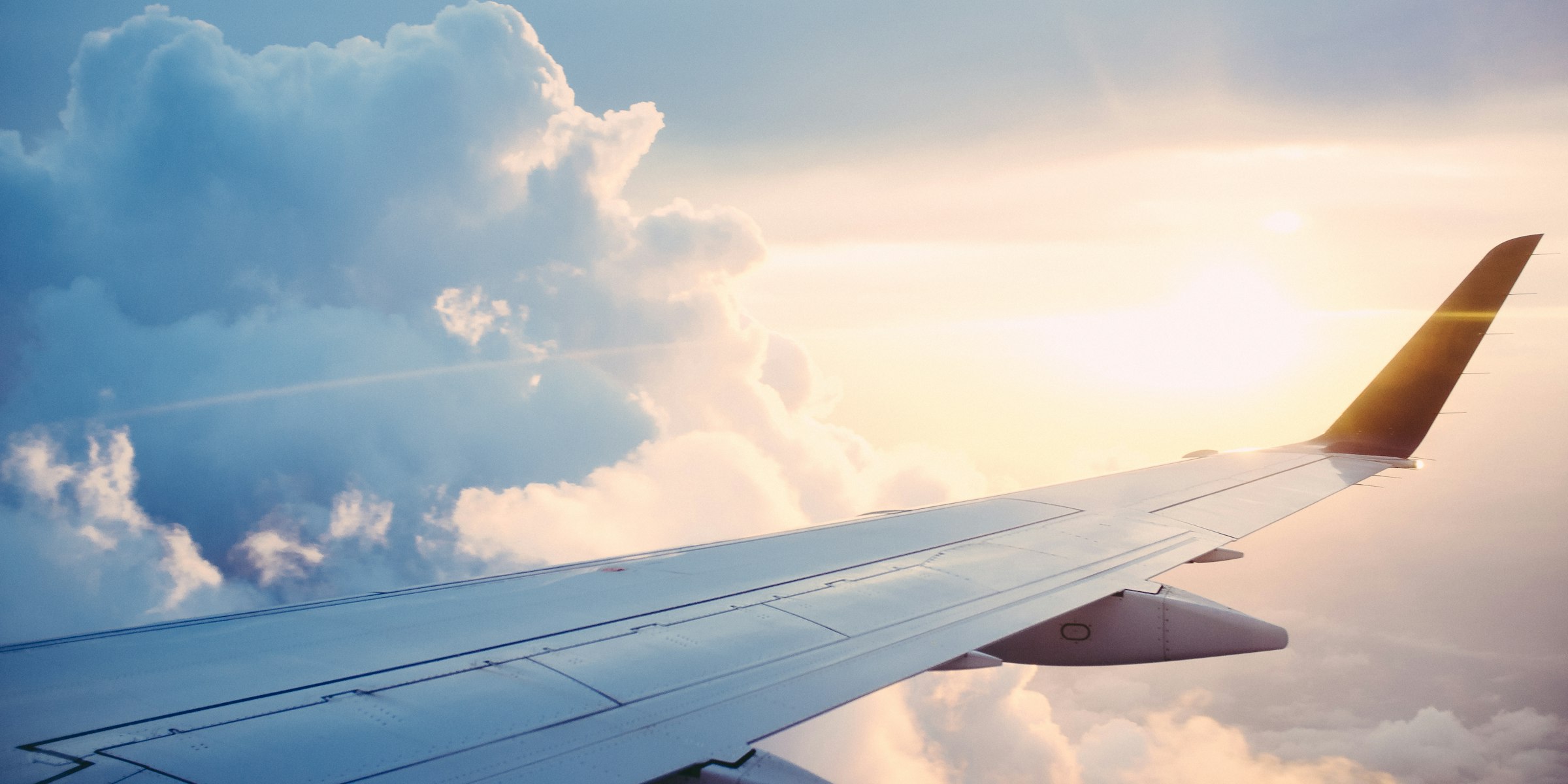Airplane wing above clouds at sunrise